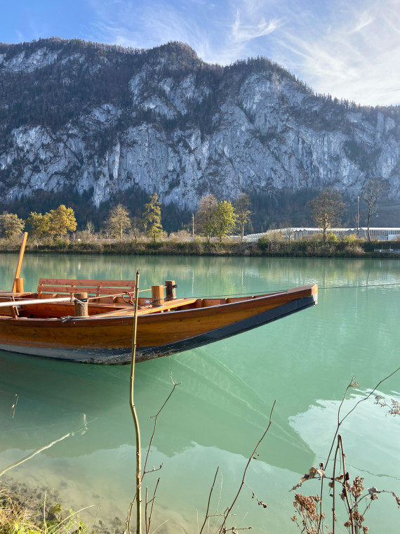 Innfahrt Holzboot auf dem türkisfarbenen Fluss vor dem Hintergrund der Berge