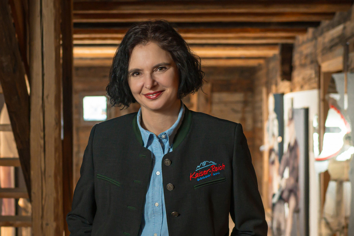 Einzelporträt einer lächelnden Dame mit dunklem Bob und tiroler Jacket farbig
