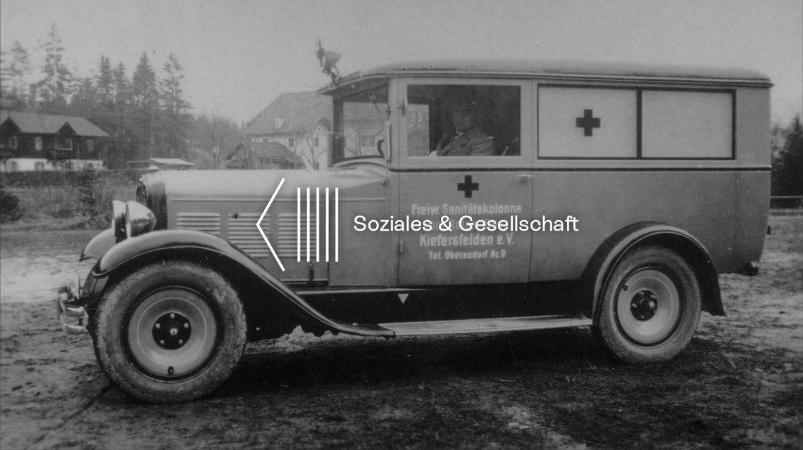 Header: historischer Rot-Kreuz Krankenwagen mit Fahrer in schwarz-weiß