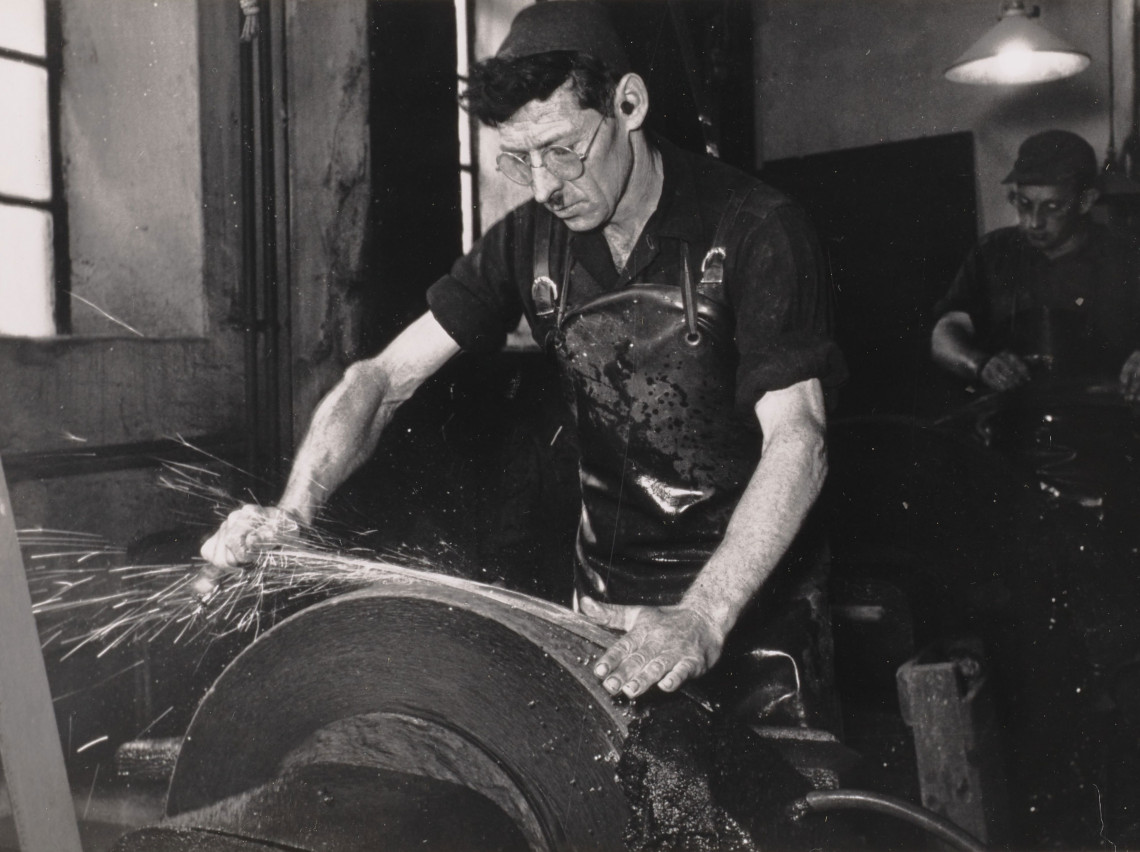 Ein Sensenschmied beim Schleifen einer Sense. Foto: 1950er Jahre
